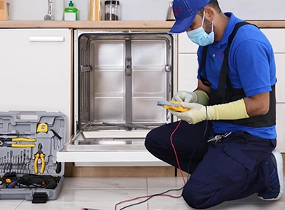 Plumber Inspecting Dishwasher with Tools Spread on Kitchen Floor