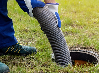 Worker in Gloves Performing Drain Cleaning on Lawn