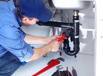 Plumber Fixing Pipe Under Sink with Wrench for Water Heater Repair