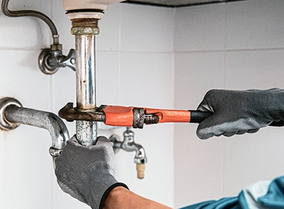 Plumber Fixing Pipes Under Sink with Wrench in Weymouth MA